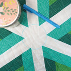 Quilt with geometric pattern and blue marking pen on a green surface
