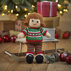 Knitted doll in a green and red outfit with Christmas decorations in the background