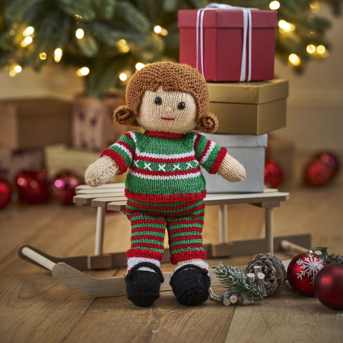 Knitted doll in a green and red outfit with Christmas decorations in the background