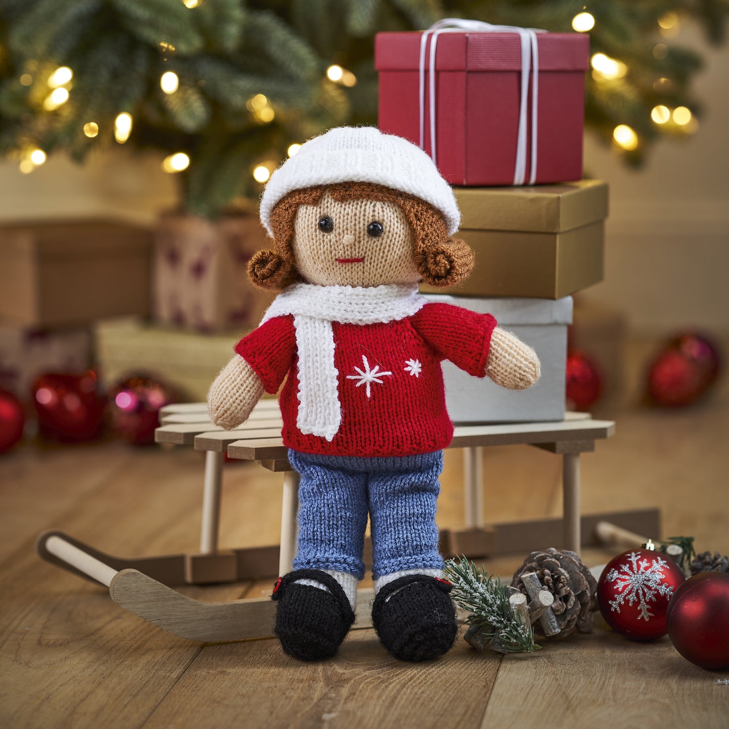 Knitted doll in winter clothing with Christmas decorations in the background