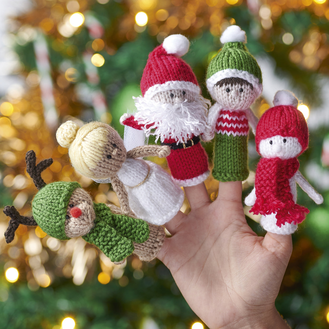 Hand holding a set of knitted finger puppets with a festive background