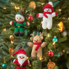 Knitted Christmas ornaments including a snowman, reindeer, and Santa Claus on a decorated tree.