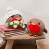 Two knitted robins on a wooden stool against a textured wall.