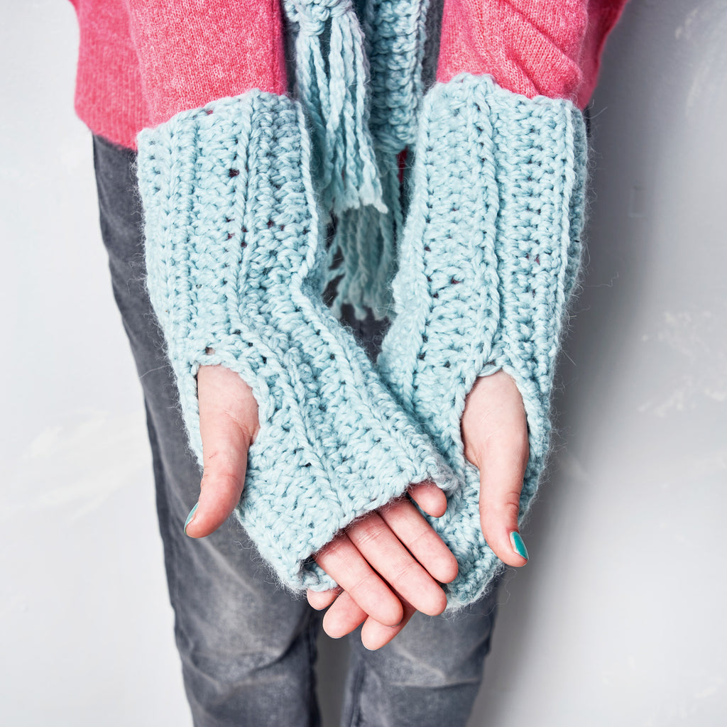Light blue fingerless gloves worn by a person on a plain background