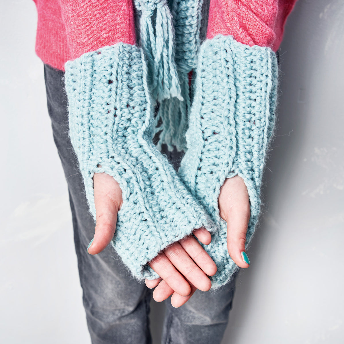 Light blue fingerless gloves worn by a person on a plain background