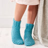 Blue knitted socks worn by a person on a light wooden floor.