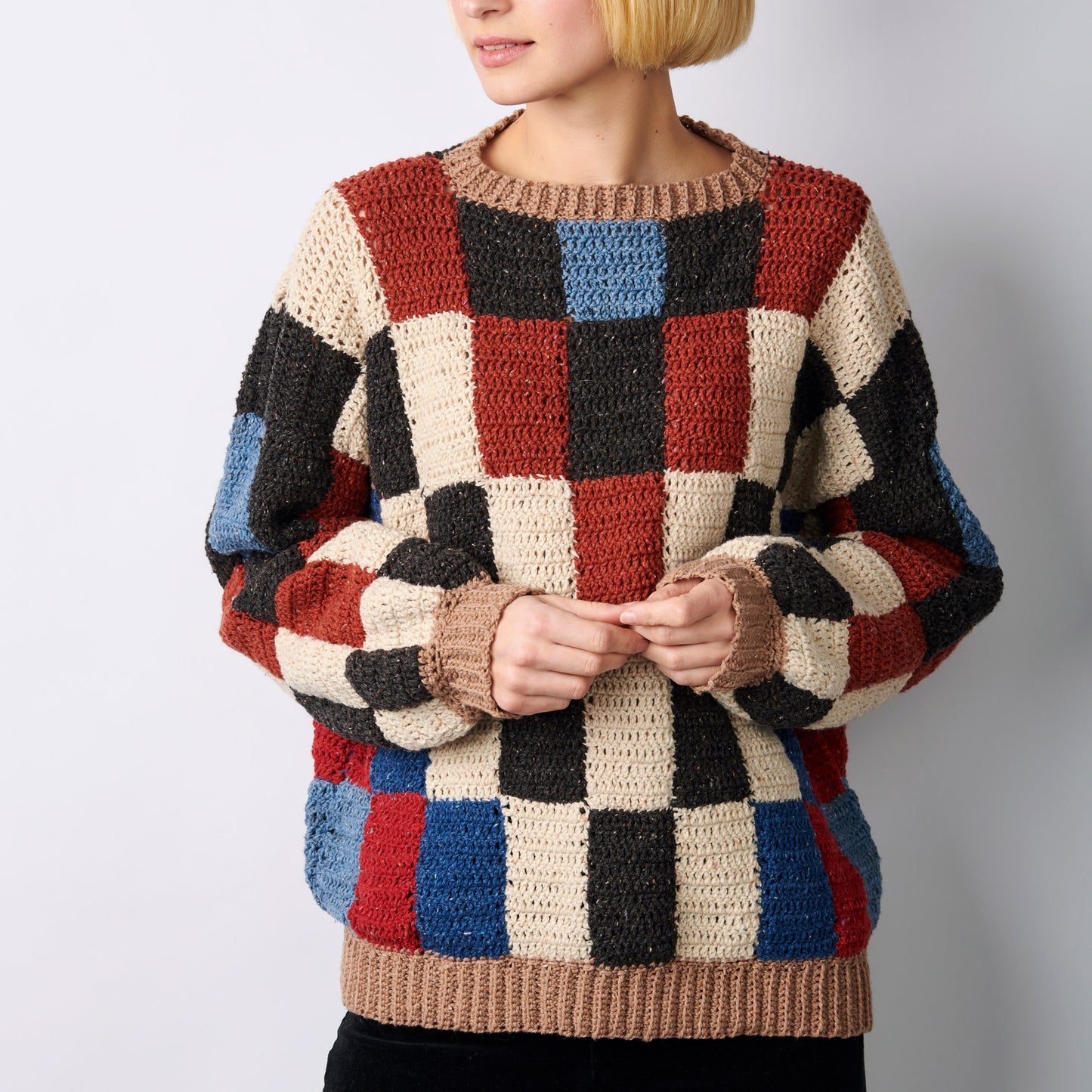 Person wearing a colorful checkered sweater against a plain background