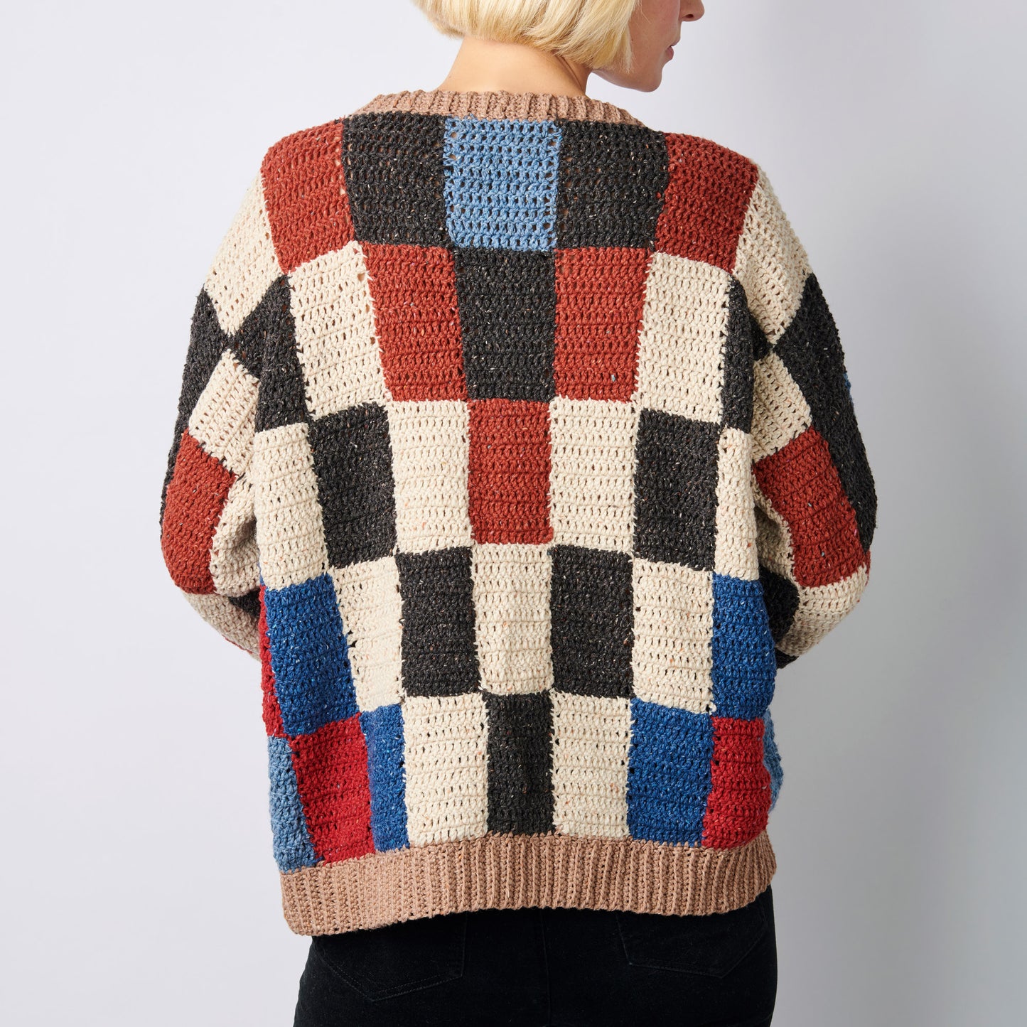 Colorful checkered sweater worn by a person on a plain background