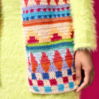 Colorful crocheted patterned pouch held by a person wearing a green sweater.