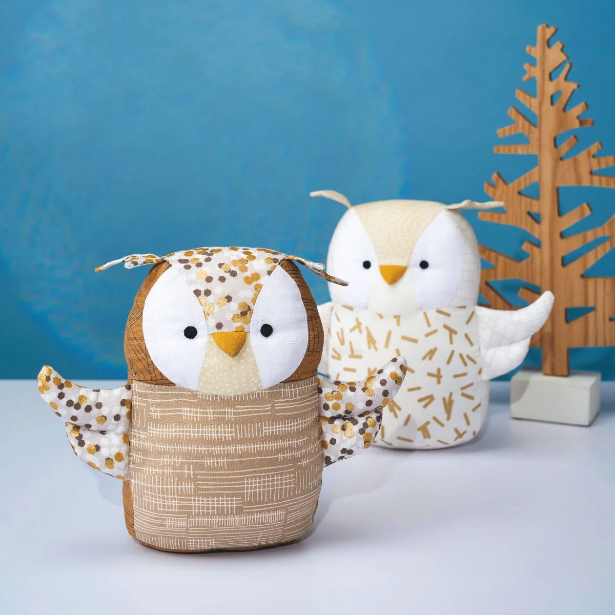 Two owl-shaped containers with a wooden tree decoration on a blue background