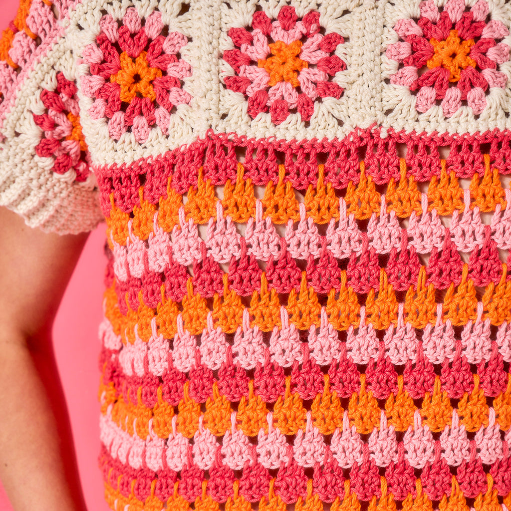 Close-up of a colorful crochet pattern with pink, orange, and white colors.