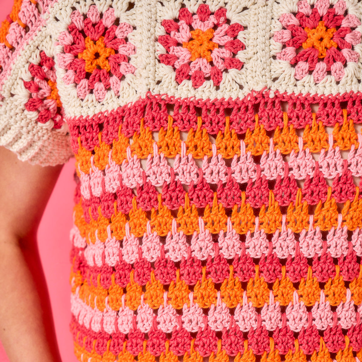 Close-up of a colorful crochet pattern with pink, orange, and white colors.