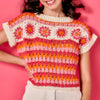 Woman wearing a colorful crochet top with a pink background