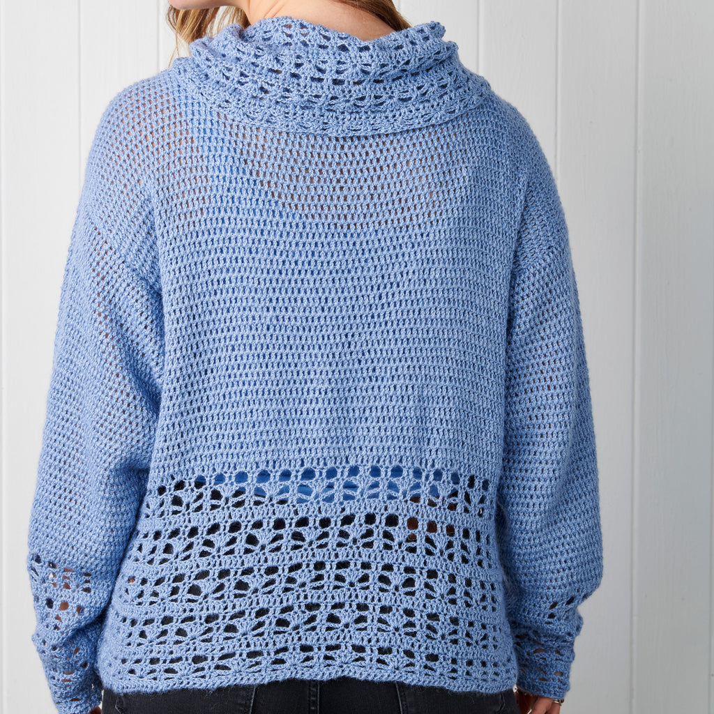 Blue crochet sweater worn by a person against a white background