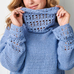 Person wearing a blue crochet sweater with a white background