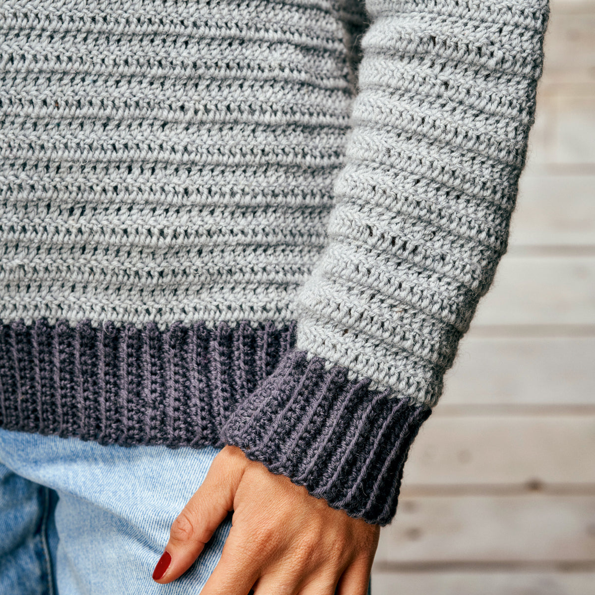 Close-up of a person wearing a gray and black striped sweater with a blurred background