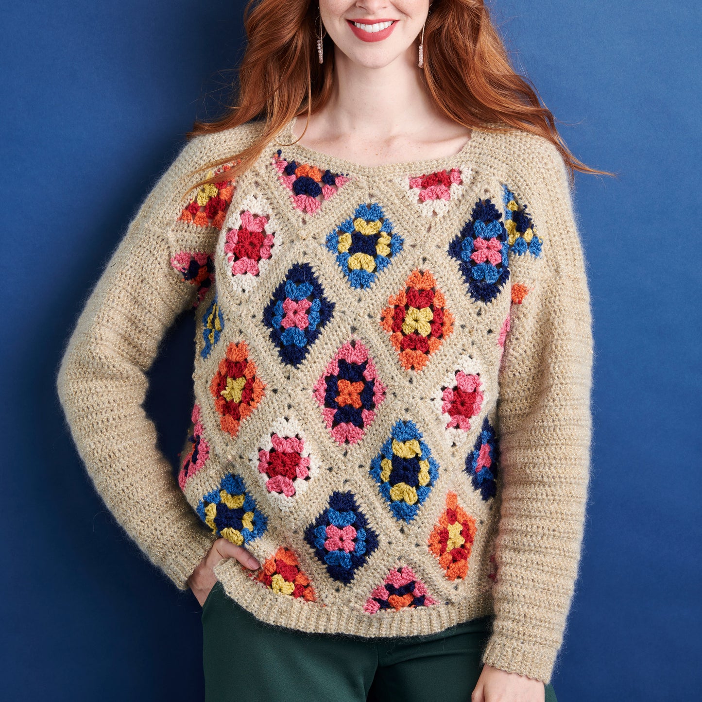 Person wearing a colorful crochet sweater against a blue background