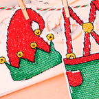 Two cross stitch patches of a red elf hat and green pants on a white background.