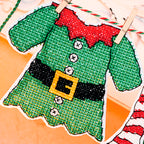 Cross-stitched green elf sweater with red collar on a fabric background