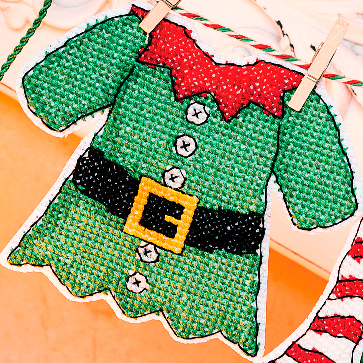 Cross-stitched green elf sweater with red collar on a fabric background