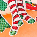Colorful Christmas-themed socks with red and green patterns on an orange background