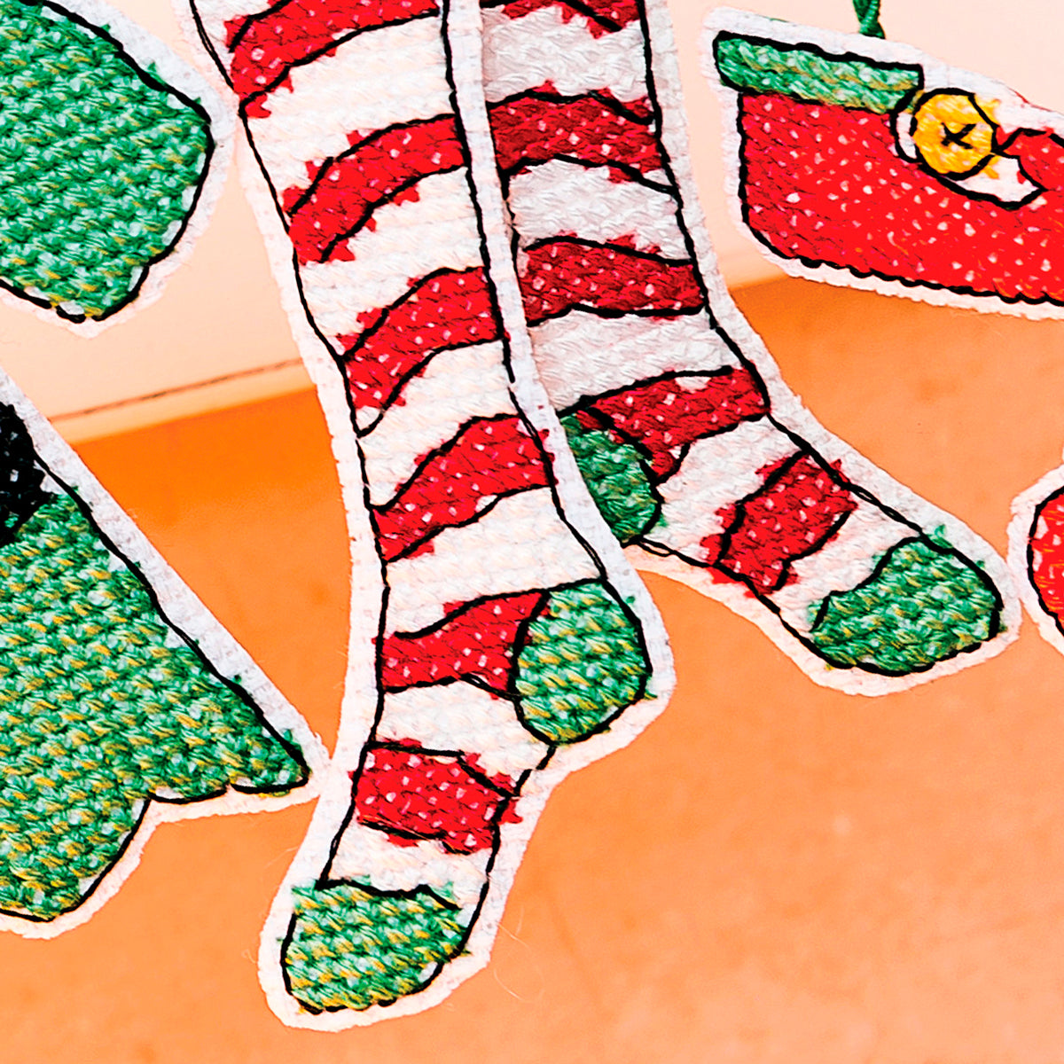 Colorful Christmas-themed socks with red and green patterns on an orange background