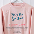 A pink jumper with the words 'bring me sunshine' on the front