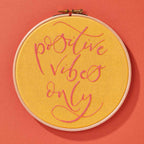 A yellow embroidery hoop with the words 'positive vibes only'