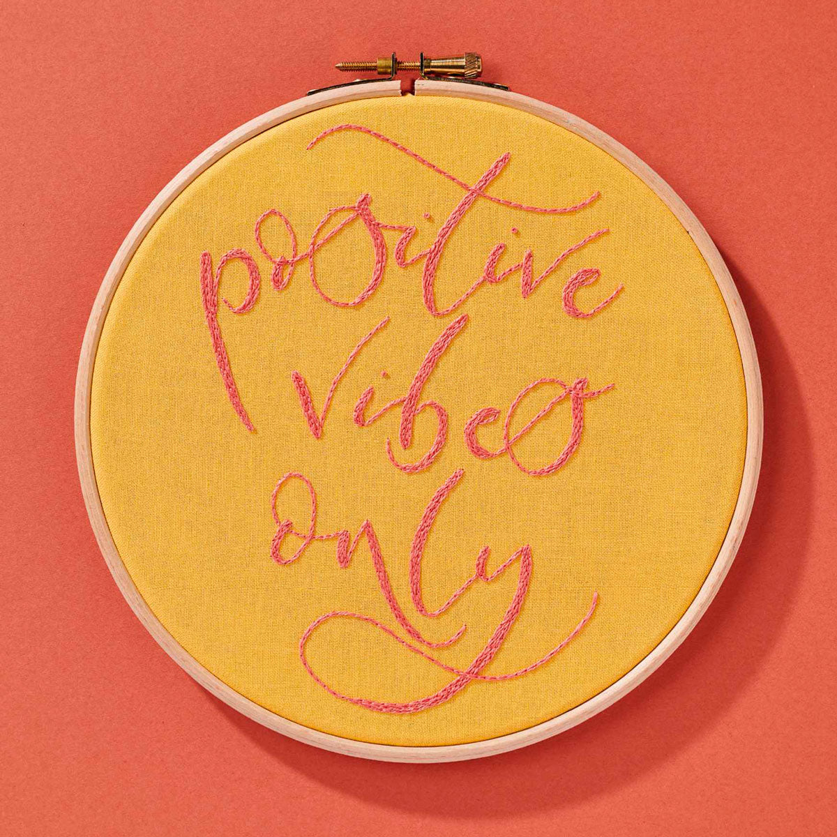 A yellow embroidery hoop with the words 'positive vibes only'