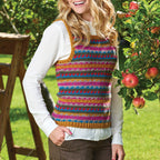 Woman wearing a colorful striped vest outdoors with greenery and apples in the background