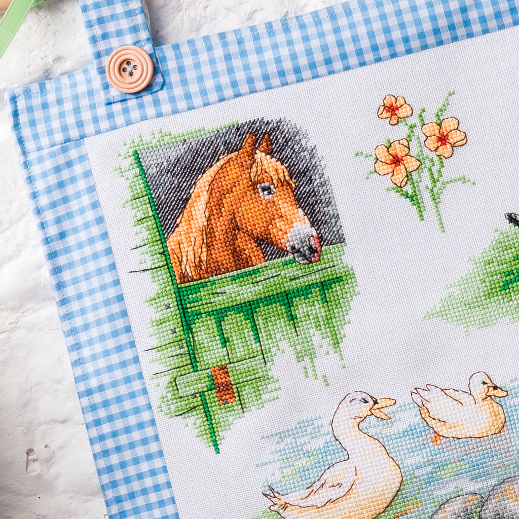 Cross-stitched design with a horse and ducks on a checkered fabric background