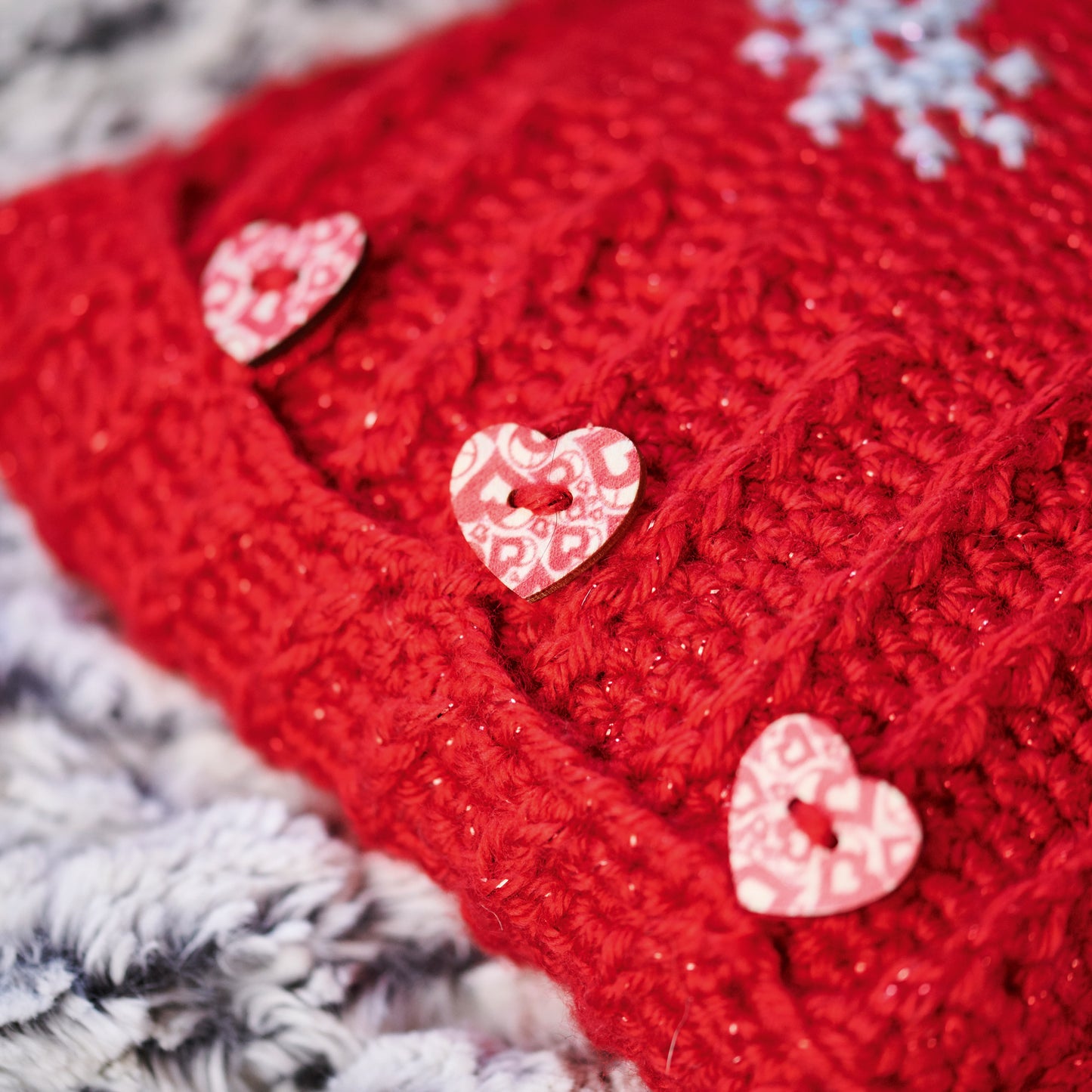 Red knitted fabric with heart-shaped buttons on a textured surface