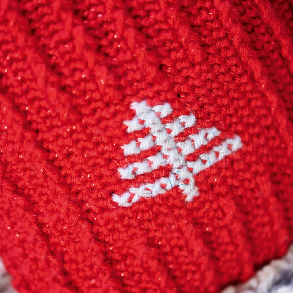 Close-up of a red crocheted fabric with a white embroidered design on a textured background.