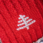 Close-up of a red crocheted fabric with a white embroidered design on a textured background.