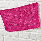 Pink crocheted fabric on a white brick wall background