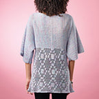 Person wearing a light blue crochet cardigan against a pink background