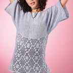 Woman wearing a light blue crochet dress against a pink background