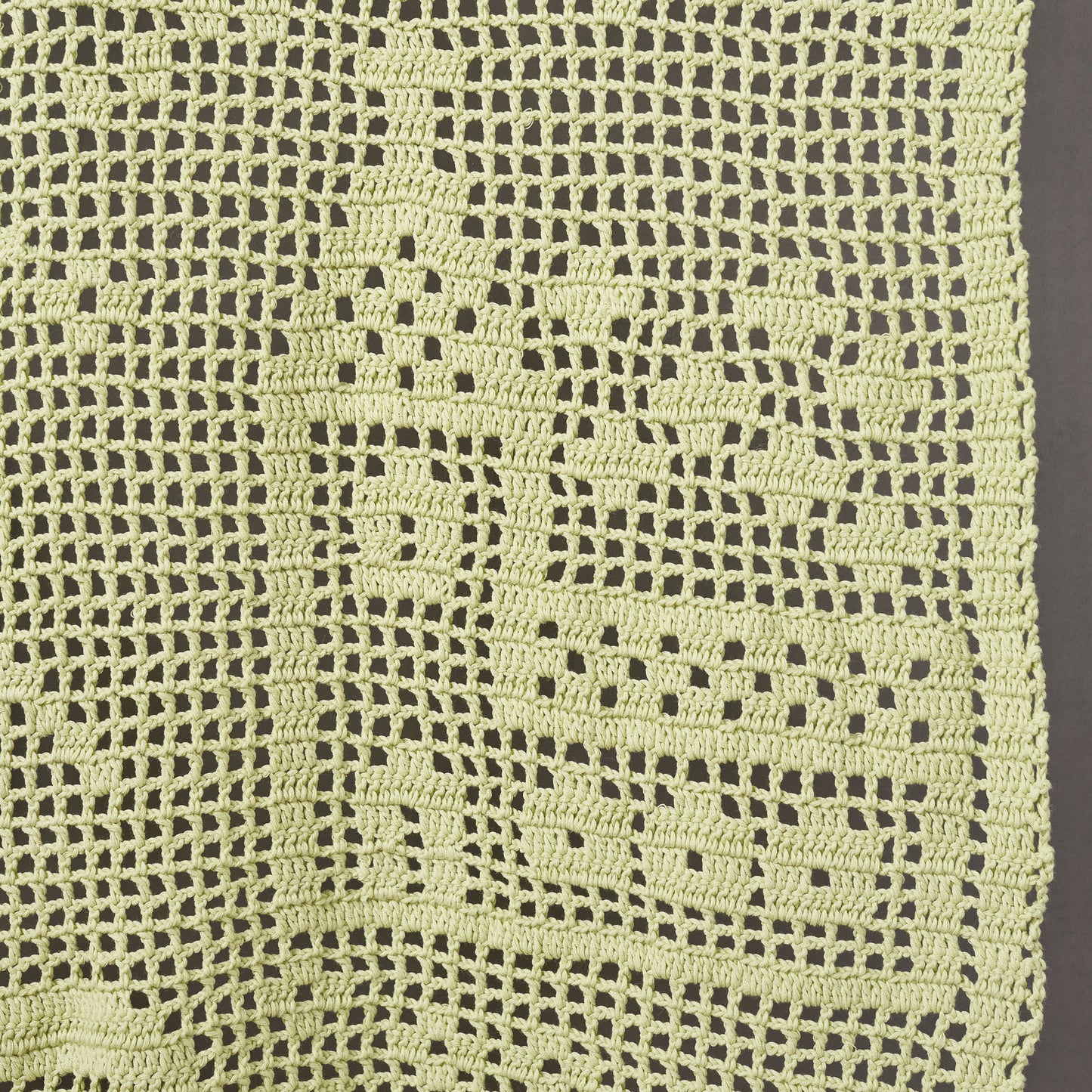 Close-up of a green crocheted fabric with a diamond pattern.