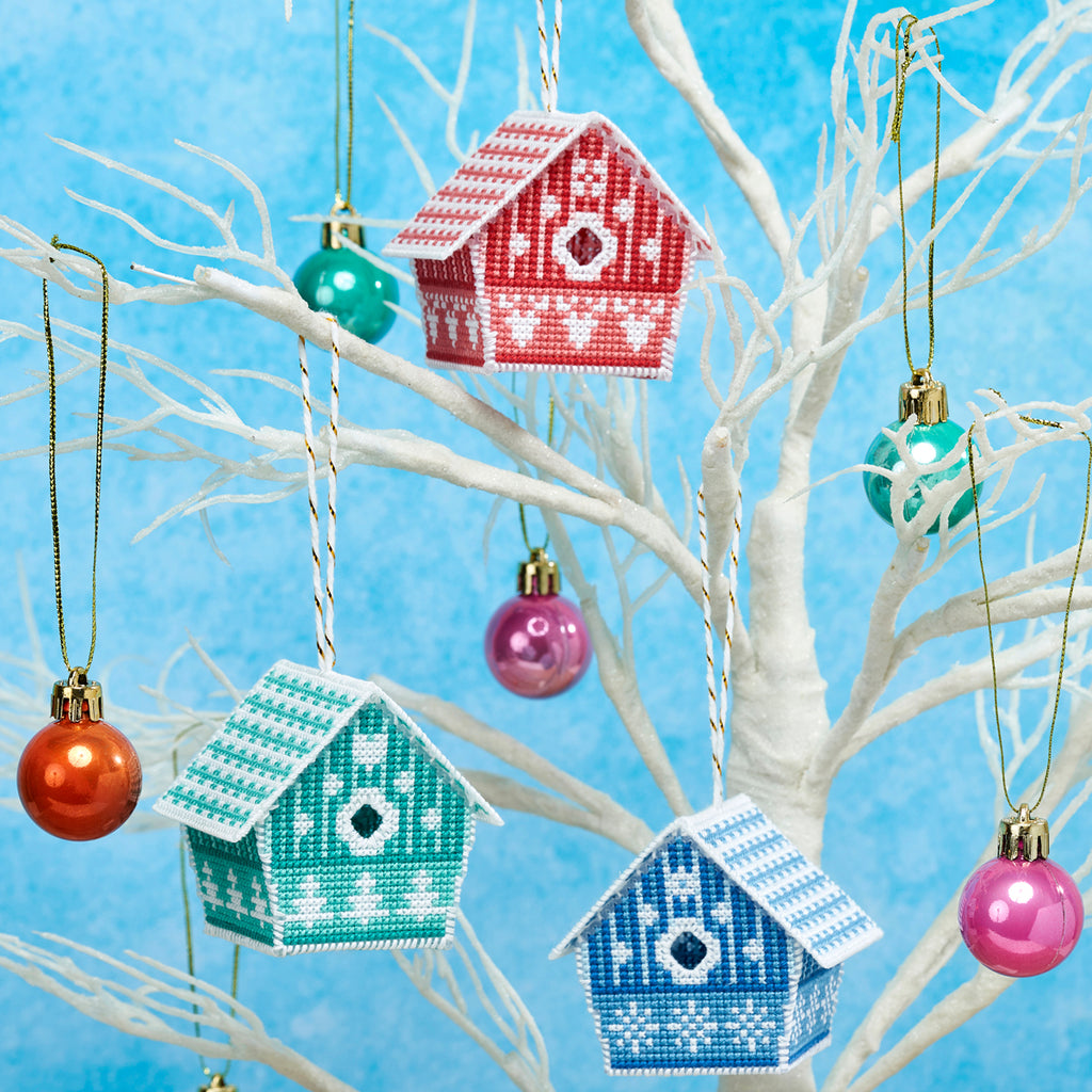 Decorative birdhouse ornaments hanging on a white branch against a blue background
