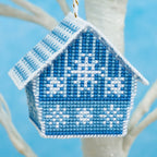 Cross-stitched blue and white house ornament on a branch with a blue background
