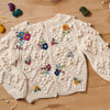 Knitted cardigan with floral embroidery on a wooden surface