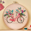 Embroidery hoop with a bicycle and floral design on a beige background