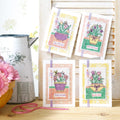 Four cross-stitched cards with floral designs on a wooden surface.