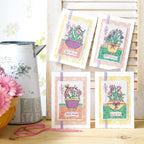 Four cross-stitched cards with floral designs on a wooden surface.