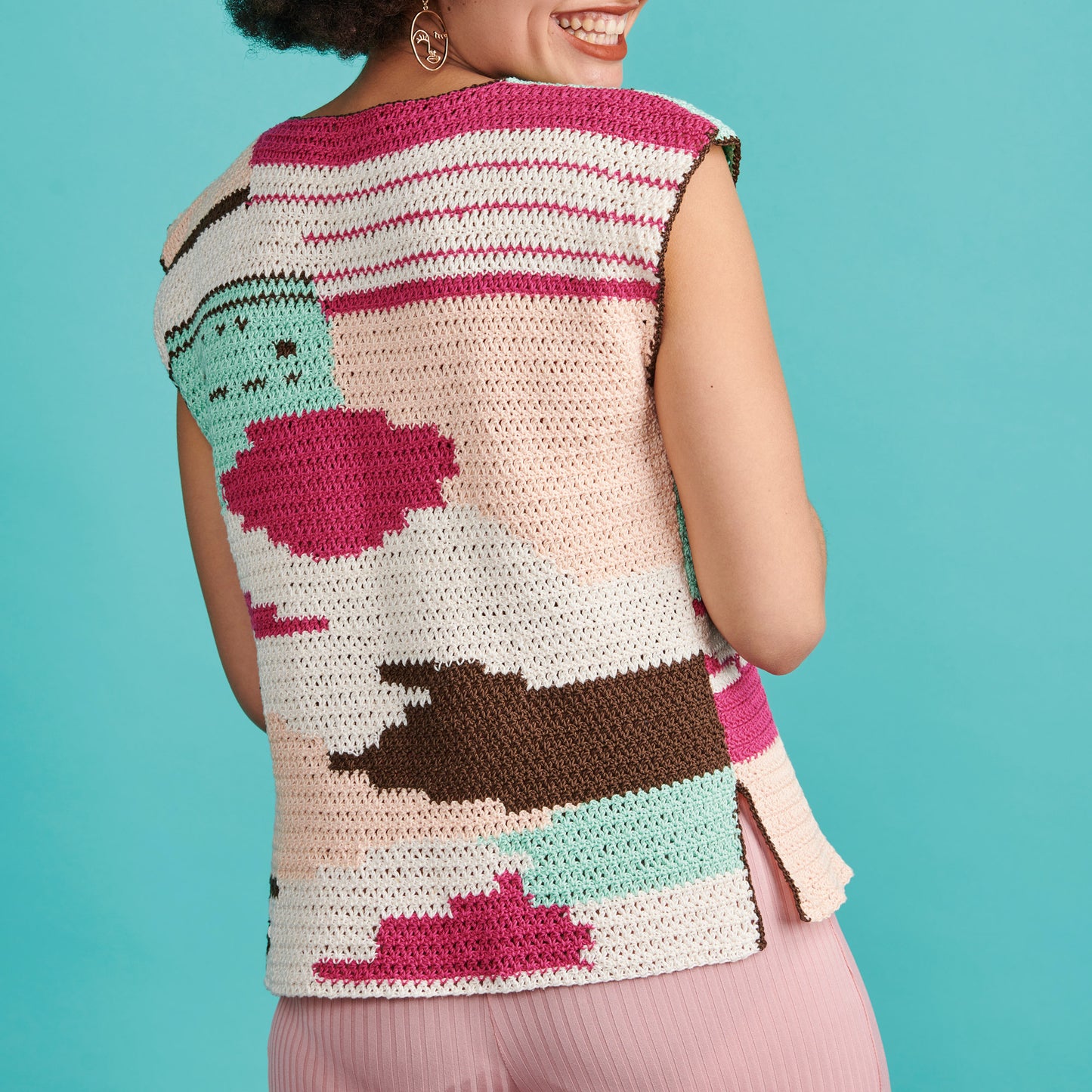 Person wearing a colorful crochet vest against a blue background