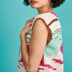 Woman wearing a colorful crochet top against a blue background