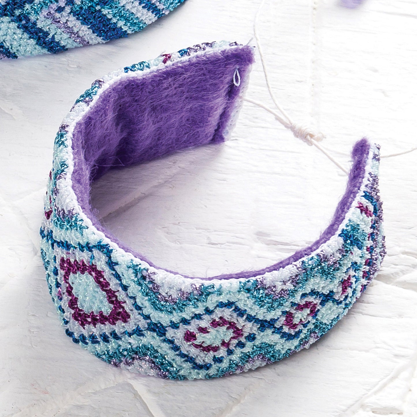 Decorative headband with purple interior on a light wooden surface