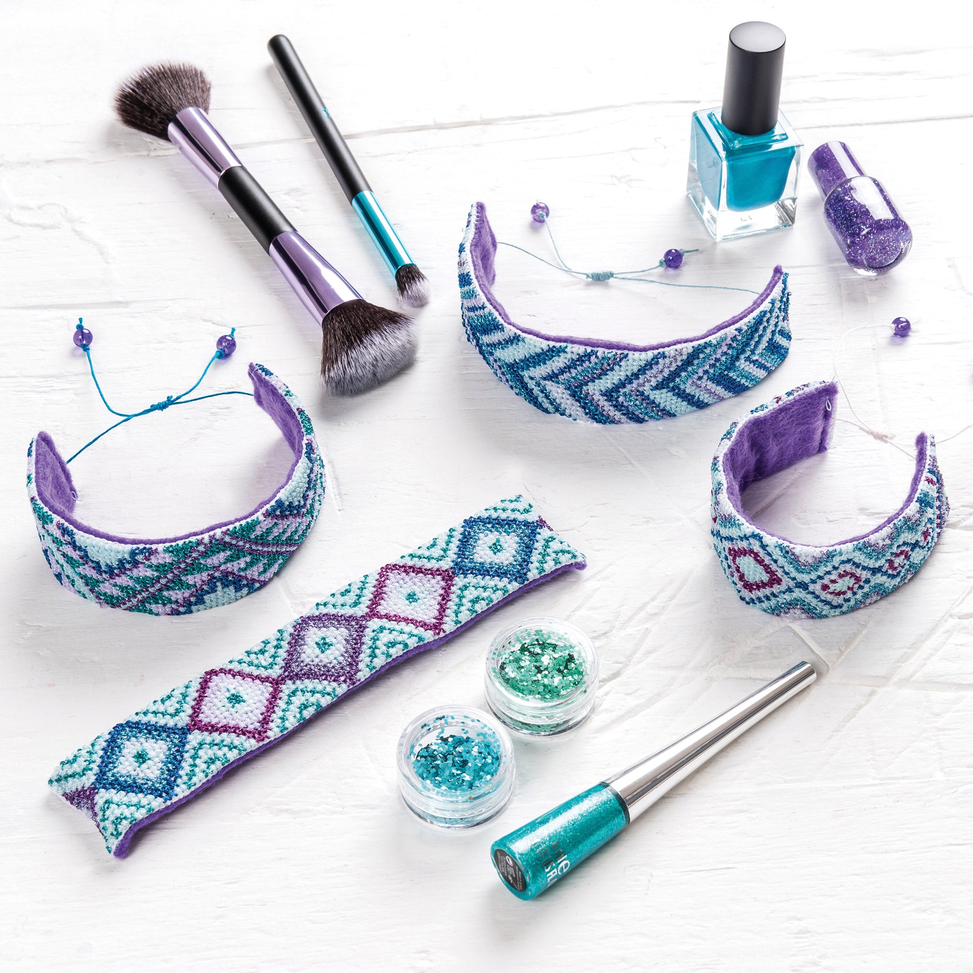 Makeup brushes, nail polish, and decorative headbands on a white background