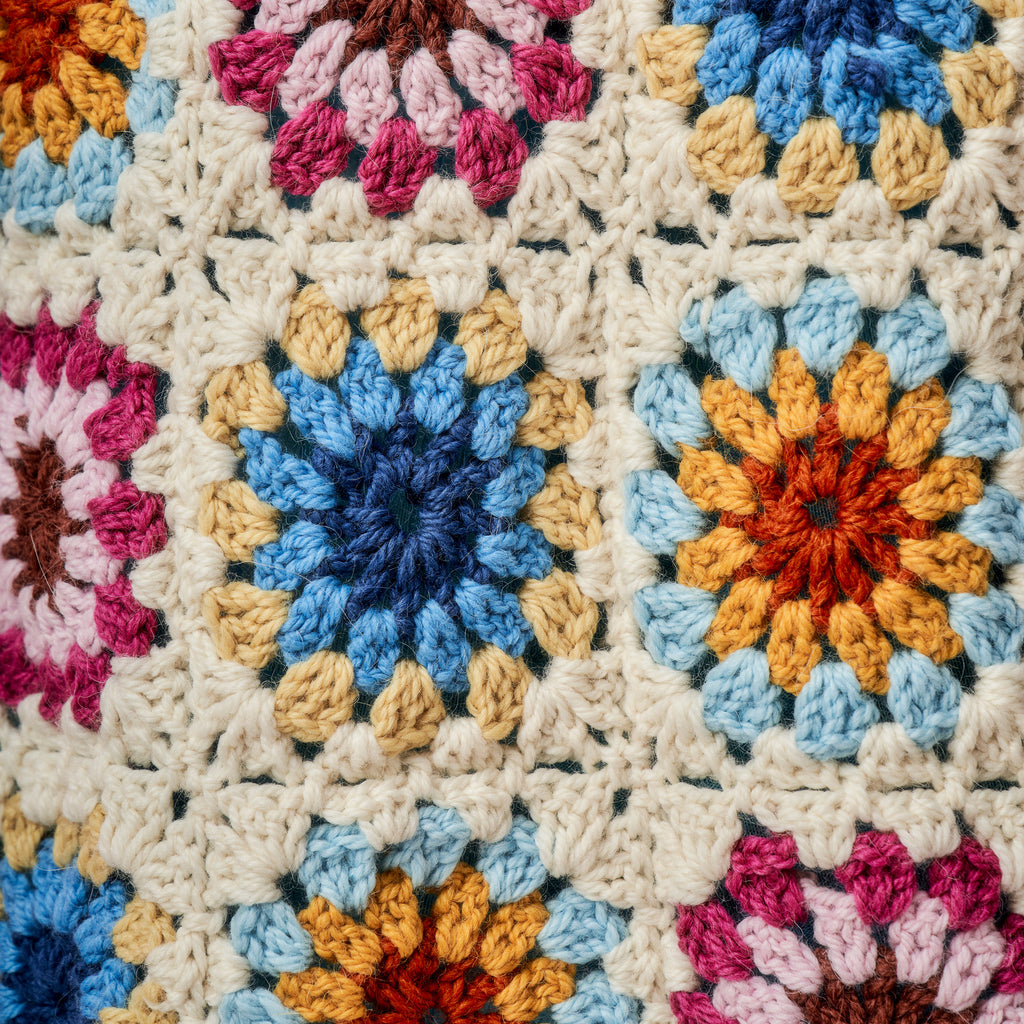 Close-up of a colorful crocheted blanket with various patterns.