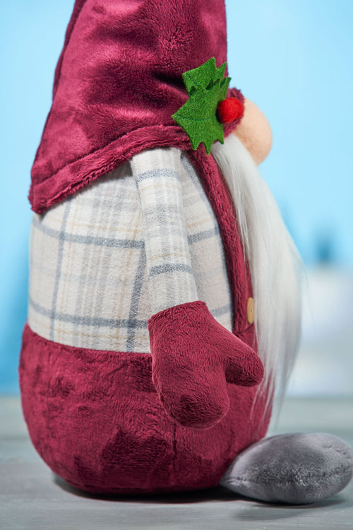 Plush gnome toy with red outfit and plaid pants on a light blue background